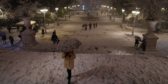 People walk on the snow-covered Syntagma square during a snowstorm in Athens, Griekeland, Maandag, Jan.. 24, 2022.