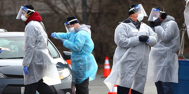 Health care workers administer COVID-19 tests in the parking lot at McCoy Stadium in Pawtucket, Rhode Island, on Dec. 8, 2020.