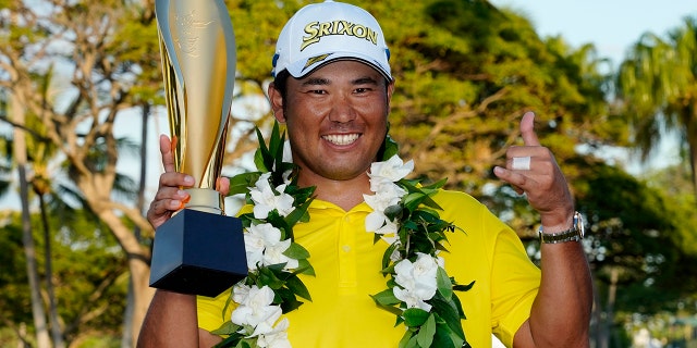 Hideki Matsuyama, of Japan, holds the champions trophy after the final round of the Sony Open golf tournament, Domenica, Jan. 16, 2022, at Waialae Country Club in Honolulu.