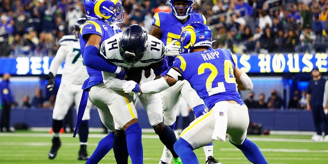 DK Metcalf of the Seattle Seahawks is tackled by Taylor Rapp and Jalen Ramsey of the Los Angeles Rams at SoFi Stadium on Dec. 21, 2021, in Inglewood, California.