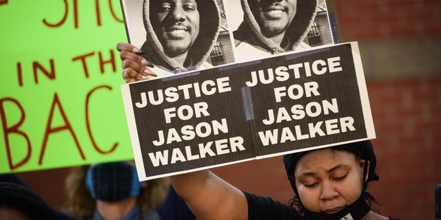 Pandora Harrington holds up a sign with an image of Jason Walker during a demonstration in front of the Fayetteville Police Department on Sunday.
