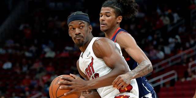 Miami Heat forward Jimmy Butler, 左, looks to get around Houston Rockets guard Jalen Green during the first half of an NBA basketball game Friday, 12月. 31, 2021, ヒューストンで.