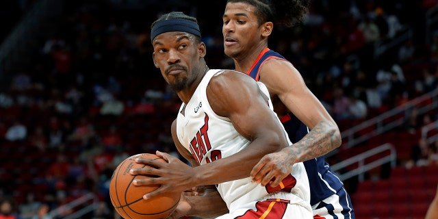 Miami Heat forward Jimmy Butler, 左, looks to get around Houston Rockets guard Jalen Green during the first half of an NBA basketball game Friday, 12月. 31, 2021, ヒューストンで.