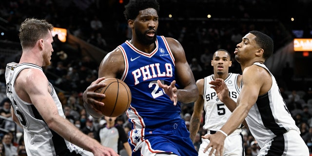 Philadelphia 76ers' Joel Embiid (21) tangles with San Antonio Spurs' Jakob Poeltl, 左, Keldon Johnson, 正しい, and Dejounte Murray during the first half of an NBA basketball game, 日曜日, 1月. 23, 2022, in San Antonio.