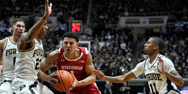 Wisconsin's Johnny Davis (1) goes to the basket against Purdue's Jaden Ivey (23) and Isaiah Thompson (11) during the first half of an NCAA basketball game, 月曜, 1月. 3, 2022, in West Lafayette, Ind.