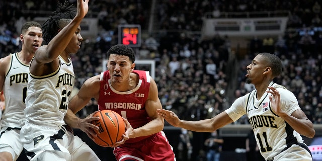 Wisconsin's Johnny Davis (1) goes to the basket against Purdue's Jaden Ivey (23) and Isaiah Thompson (11) during the first half of an NCAA basketball game, 月曜, 1月. 3, 2022, in West Lafayette, Ind.