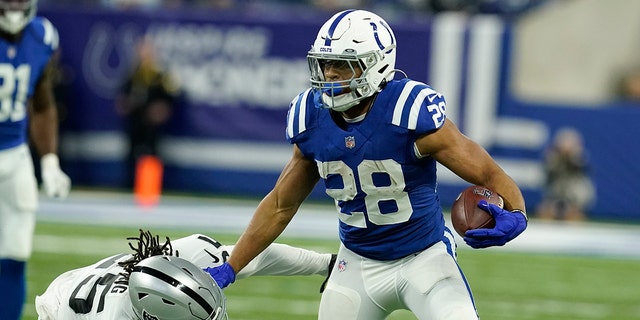 Indianapolis Colts running back Jonathan Taylor (28) tries to break a tackle by Las Vegas Raiders free safety Trevon Moehrig (25) during the first half of an NFL football game, Sunday, Jan. 2, 2022, in Indianapolis. 