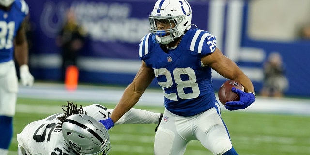 Indianapolis Colts running back Jonathan Taylor (28) tries to break a tackle by Las Vegas Raiders free safety Trevon Moehrig (25) during the first half of an NFL football game, Sunday, Jan. 2, 2022, in Indianapolis.