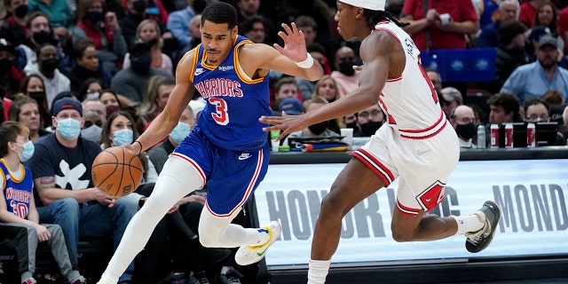 Golden State Warriors guard Jordan Poole, left, drives against Chicago Bulls guard Ayo Dosunmu during the first half of an NBA basketball game in Chicago, Friday, Jan. 14, 2022.