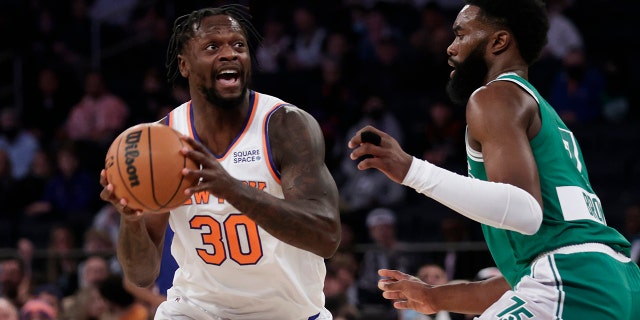 New York Knicks forward Julius Randle (30) looks to pass the ball around Boston Celtics guard Jaylen Brown during the first half of a game Thursday, Jan. 6, 2022, in New York.