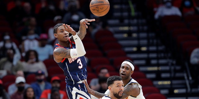 Houston Rockets guard Kevin Porter Jr. (3) passes the ball over Denver Nuggets guard Austin Rivers, middle and forward Will Barton, right, during the first half of an NBA basketball game Saturday, Jan. 1, 2022, in Houston.