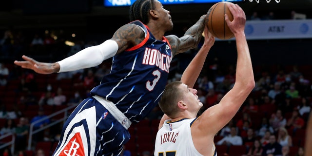 Houston Rockets guard Kevin Porter Jr. (3) reaches over to block the shot attempt by Denver Nuggets center Nikola Jokic (15) during the first half of an NBA basketball game Saturday, Jan. 1, 2022, in Houston.