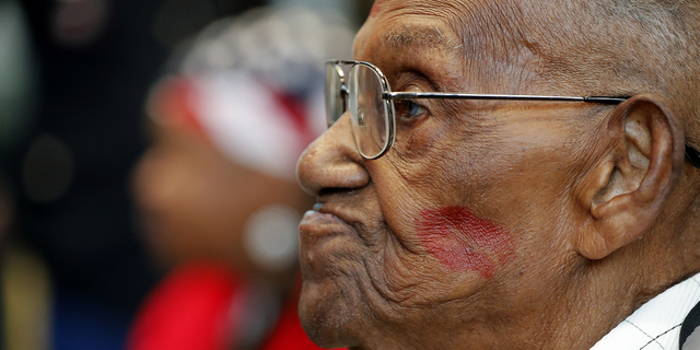 World War II veteran Lawrence Brooks sports a lipstick kiss on his cheek, planted by a member of the singing group Victory Belles, during his 110th birthday celebration.