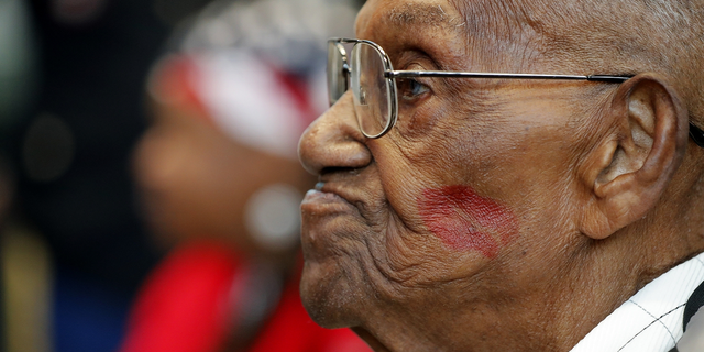 World War II veteran Lawrence Brooks sports a lipstick kiss on his cheek, planted by a member of the singing group Victory Belles, during his 110th birthday celebration.