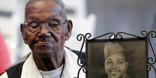 World War II veteran Lawrence Brooks holds a photo of him taken in 1943, when he celebrated his 110th birthday at the National World War II Museum in New Orleans, on Sept. 12, 2019. (AP/Gerald Herbert)