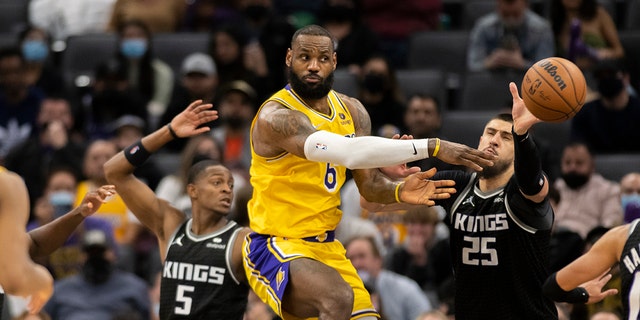 Penyerang Los Angeles Lakers LeBron James (6) melakukan operan saat dipertahankan oleh guard Sacramento Kings De'Aaron Fox (5) dan center Alex Len (25) pada paruh kedua pertandingan bola basket NBA di Sacramento, California, Rabu, Jan.  12, 2022. The Kings menang 125-116.