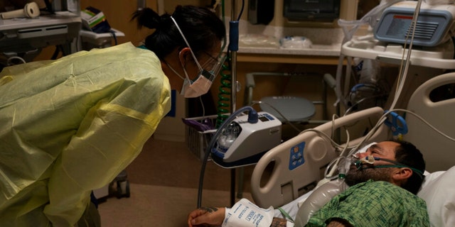 BESTAND - Geregistreerde verpleegster Emily Yu, links, praat met Paul Altamerano, een 50-jarige patiënt met COVID-19, in het Providence Holy Cross Medical Center in Los Angeles, 13 december 2021. Ziekenhuizen in de Verenigde Staten zijn verontwaardigd over de omicron-variant en het betreden van een staat van wanorde die verschilt van eerdere mutaties van COVID-19.  (AP Photo/Jae C. Hong, bestand) 