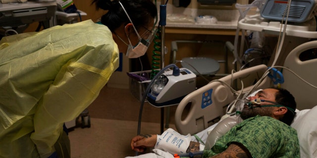 FILE - Registered nurse Emily Yu, left, talks to Paul Altamirano, a 50-year-old COVID-19 patient, at Providence Holy Cross Medical Center in Los Angeles, Dec. 13, 2021. Hospitals across the U.S. are feeling the wrath of the omicron variant and getting thrown into disarray that is different from earlier COVID-19 surges. (AP Photo/Jae C. Hong, File)
