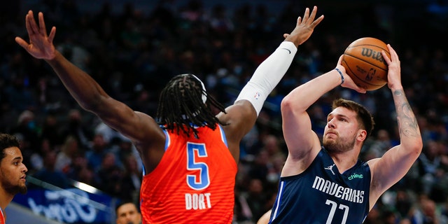 Dallas Mavericks guard Luka Doncic (77) attempts to shoot as Oklahoma City Thunder forward Luguentz Dort (5) defends during the first half of an NBA basketball game, 星期一, 一月. 17, 2022, 在达拉斯.