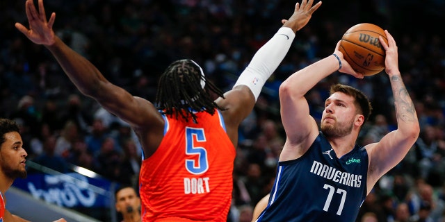 Dallas Mavericks guard Luka Doncic (77) attempts to shoot as Oklahoma City Thunder forward Luguentz Dort (5) defends during the first half of an NBA basketball game, 月曜, 1月. 17, 2022, ダラスで.