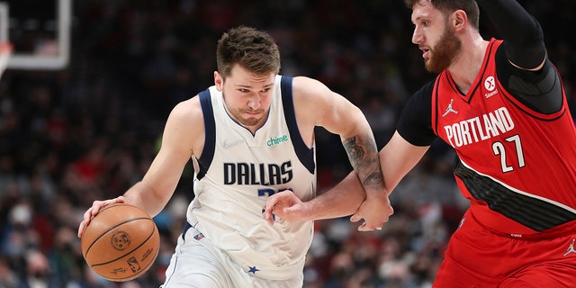 Dallas Mavericks guard Luka Doncic drives past Portland Trail Blazers center Jusuf Nurkic during the first half of an NBA basketball game in Portland, Ore., Wednesday, Jan. 26, 2022.