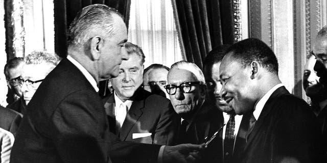 President Lyndon Johnson hands a souvenir pen to the Rev. Dr. Martin Luther King Jr. after signing the Voting Rights Act at the U.S. Capitol in Washington on Aug. 6, 1965.