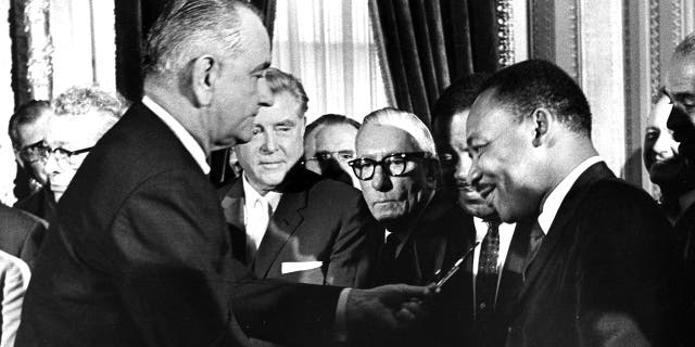 President Lyndon Johnson hands a souvenir pen to the Rev. Dr. Martin Luther King Jr. after signing the Voting Rights Act at the U.S. Capitol in Washington on Aug. 6, 1965.