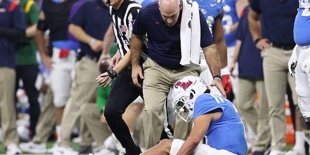 Matt Corral #2 of the Mississippi Rebels is looked over by a trainer after being injured against the Baylor Bears during the first quarter in the Allstate Sugar Bowl at Caesars Superdome on January 01, 2022 in New Orleans, Louisiana.