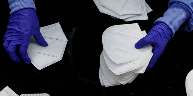 FILE PHOTO: A workers inspects an N95 respirator during manufacturing at Protective Health Gear (PHG) in Paterson, New Jersey, U.S., January 14, 2022. 