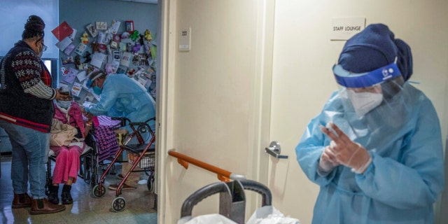 A nursing home resident, second from left, at Harlem Center for Nursing and Rehabilitation, is given a COVID-19 vaccine prepared and administered by CVS pharmacists, Jan. 15, 2021, in New York.