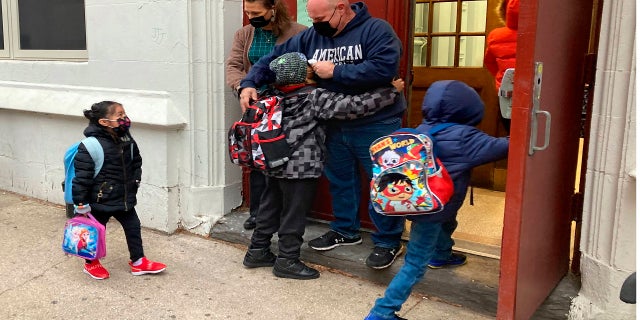 John Marro, the dean of students at P.S. 347, The American Sign Language and English Lower School, in New York, takes students' temperatures as they arrive Monday on the first day after the holiday break.