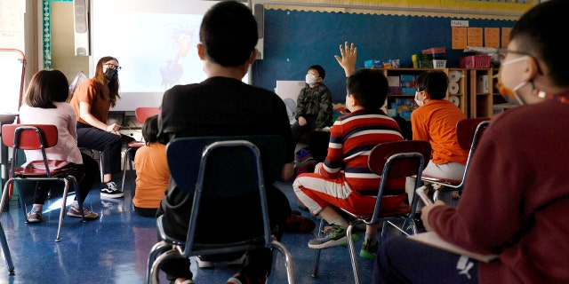 A teacher gives a lesson to masked students in their classroom at Yung Wing School P.S. 124 on Sept. 27, 2021, in New York City.