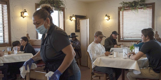 A worker wearing a protective mask and gloves disinfects tables at Pecos River Cafe in Carlsbad, New Mexico, U.S., on Friday, Sept. 11, 2020. 