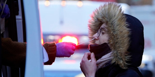 A woman wearing a winter coat gets tested for COVID-19 at a mobile testing site in New York, Tuesday, Jan. 11, 2022.  (AP Photo/Seth Wenig) 
