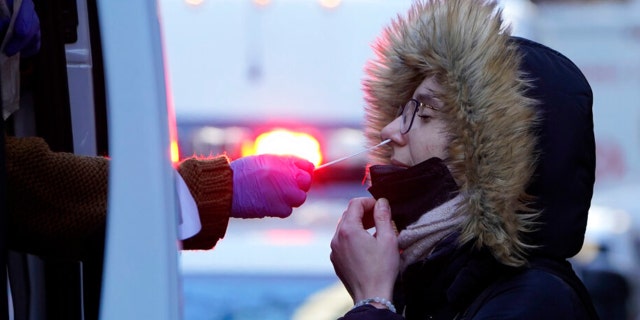 A woman wearing a winter coat gets tested for COVID-19 at a mobile testing site in New York, Tuesday, Jan. 11, 2022.  (AP Photo/Seth Wenig) 