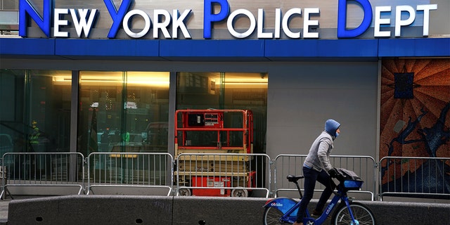 A cyclist rides past a New York Police Department station in Times Square. 