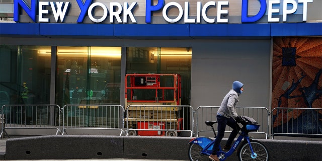 A cyclist rides past a New York Police Department station in Times Square.