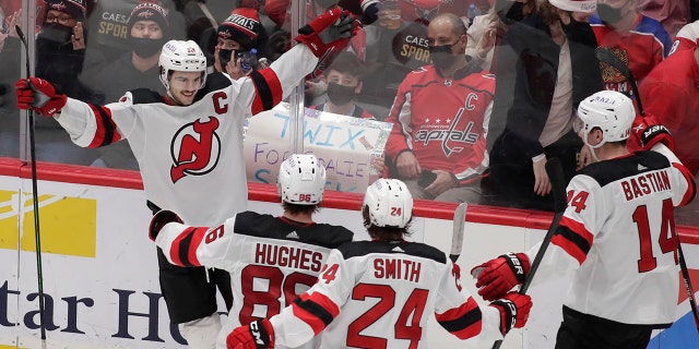 New Jersey Devils' Nico Hischier, top left, celebrates with his teammates, from left to right, Jack Hughes, Ty Smith (24) and Nathan Bastian (14) after scoring the winning goal in overtime of an NHL hockey game against the Washington Capitals, 日曜日, 1月. 2, 2022, ワシントンで.