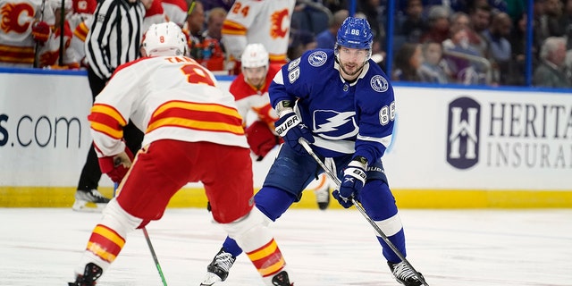 Tampa Bay Lightning right wing Nikita Kucherov (86) moves the puck towards Calgary Flames defenseman Christopher Tanev (8) during the second period of an NHL hockey game Thursday, Jan.. 6, 2022, in Tampa, Fla.