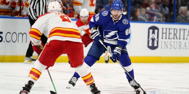Tampa Bay Lightning right wing Nikita Kucherov (86) moves the puck towards Calgary Flames defenseman Christopher Tanev (8) during the second period of an NHL hockey game Thursday, Jan.. 6, 2022, in Tampa, Fla.