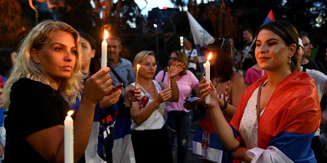 Members of the local Serbian community gather for a vigil outside a hotel where Serbia's tennis champion Novak Djokovic is reported to be staying in Melbourne on January 6, 2022, after Australia said it had cancelled Djokovic's entry visa after having failed to "provide appropriate evidence" of double vaccination or a medical exemption.