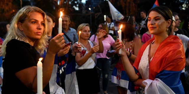 Members of the local Serbian community gather for a vigil outside a hotel where Serbia's tennis champion Novak Djokovic is reported to be staying in Melbourne on January 6, 2022, after Australia said it had cancelled Djokovic's entry visa after having failed to "provide appropriate evidence" of double vaccination or a medical exemption.
