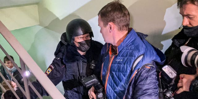 A police officer pushes photographers from a door of the apartment where Oleg Navalny, brother of jailed opposition leader Alexei Navalny, lives in Moscow, Russia Jan. 27, 2021.