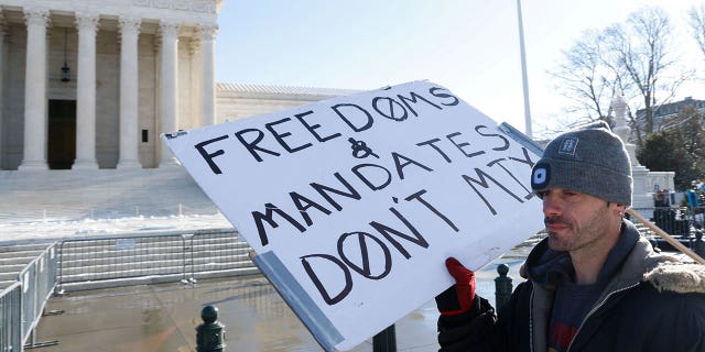 A lone protester stands outside the U.S. Supreme Court as it hears arguments against the Biden administration's nationwide vaccine-or-testing COVID-19 mandates, in Washington, U.S., January 7, 2022.