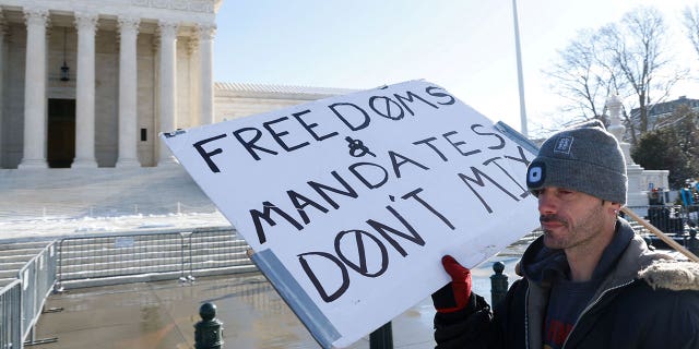 A lone protester stands outside the U.S. Supreme Court as it hears arguments against the Biden administration's nationwide vaccine-or-testing COVID-19 mandates, in Washington, U.S., January 7, 2022. REUTERS/Jonathan Ernst