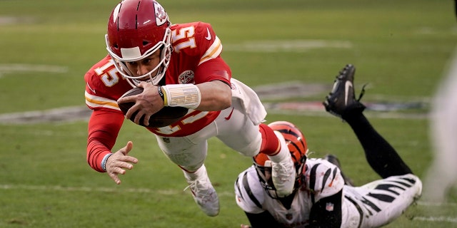 Kansas City Chiefs quarterback Patrick Mahomes (15) dives after running the ball ahead of Cincinnati Bengals defensive end Trey Hendrickson, right, during the second half of the AFC championship NFL football game, Sunday, Jan. 30, 2022, in Kansas City, Mo.