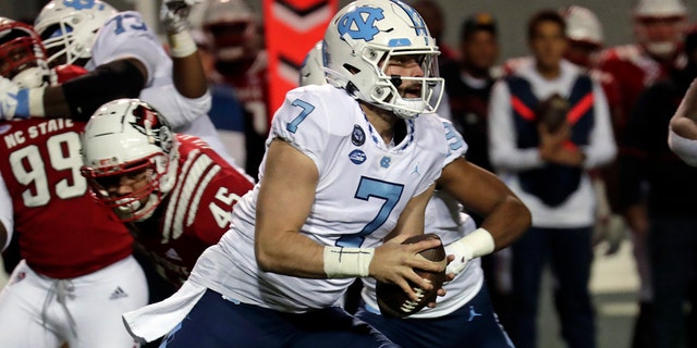 North Carolina quarterback Sam Howell (7) rolls out while being chased by North Carolina State defensive tackle Davin Vann (45) during the first half of an NCAA college football game Friday, Nov. 26, 2021, in Raleigh, N.C.