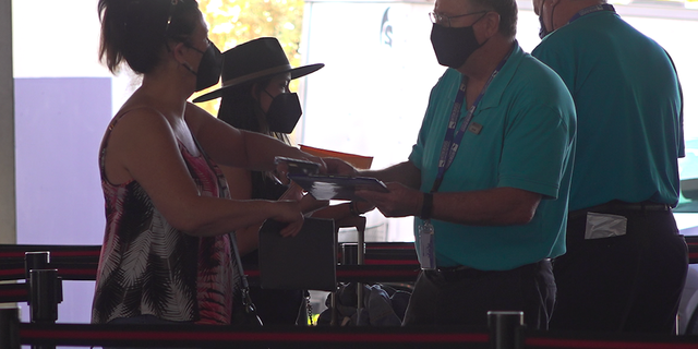 A passenger shows her negative covid-19 test to a crew member before she boards.