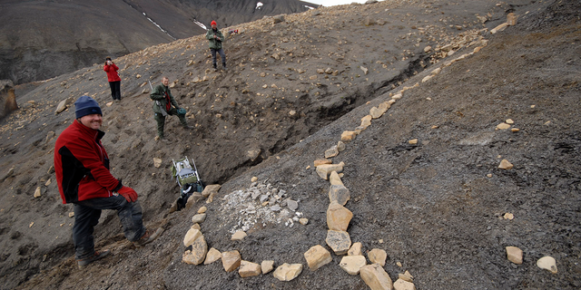 Joern Hurum (L), an assistant professor at the University of Oslo, stands next to a fossil of a "Monster" fish-like reptile in a 150 million-year-old Jurassic graveyard on the Arctic island of Spitsbergen, off Norway in this undated handout photo from the Natural History Museum, University of Oslo. 