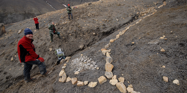 Joern Hurum (L), an assistant professor at the University of Oslo, stands next to a fossil of a "Monster" fish-like reptile in a 150 million-year-old Jurassic graveyard on the Arctic island of Spitsbergen, off Norway in this undated handout photo from the Natural History Museum, University of Oslo.